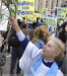 woman in priest's garb blesses protesters with 'holy' water, mocking Christ by using palm frond